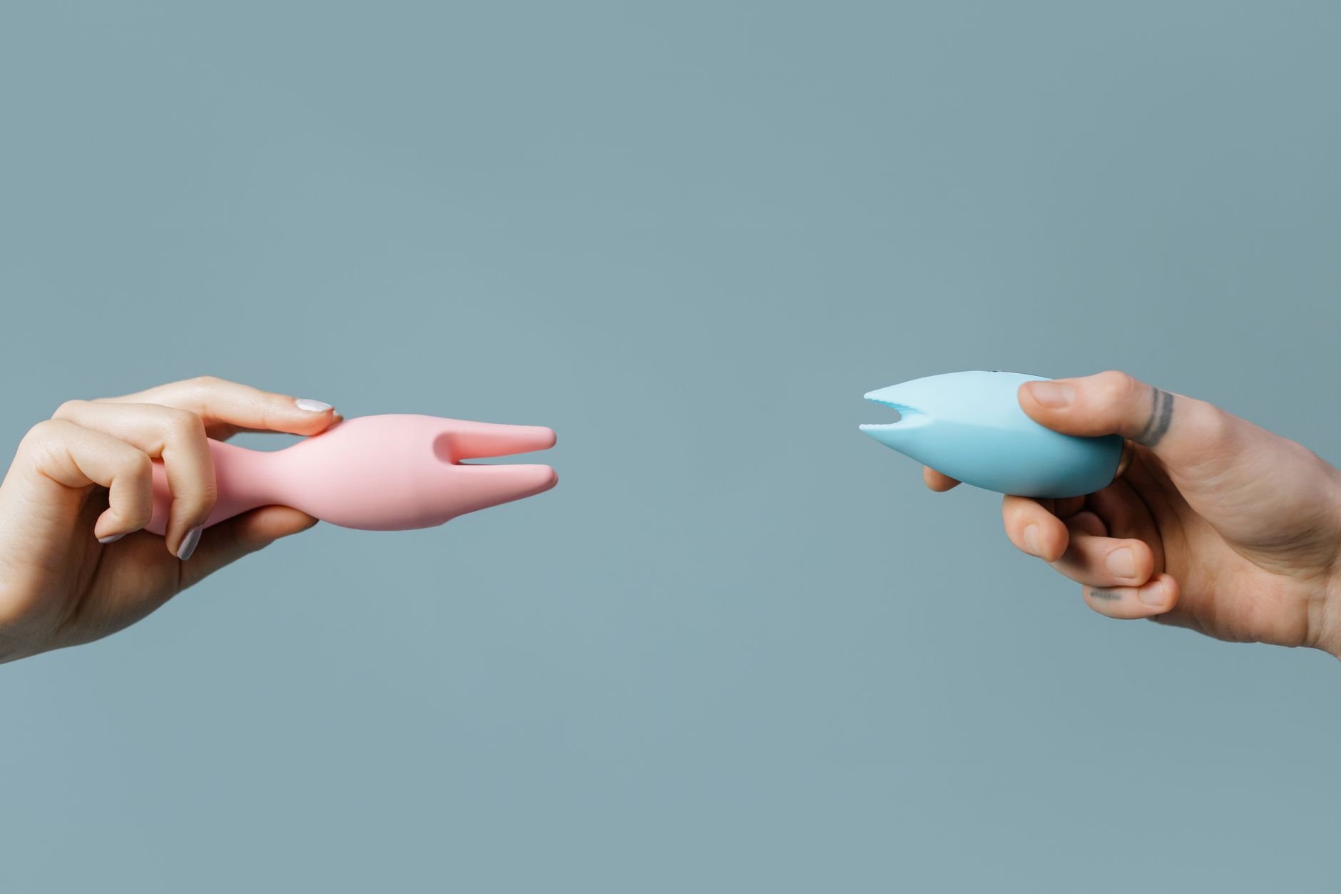 Ein junges Paar steht zusammen und hält einen blauen Vibrator in den Händen, symbolisiert gemeinsame Intimität und Vertrauen.