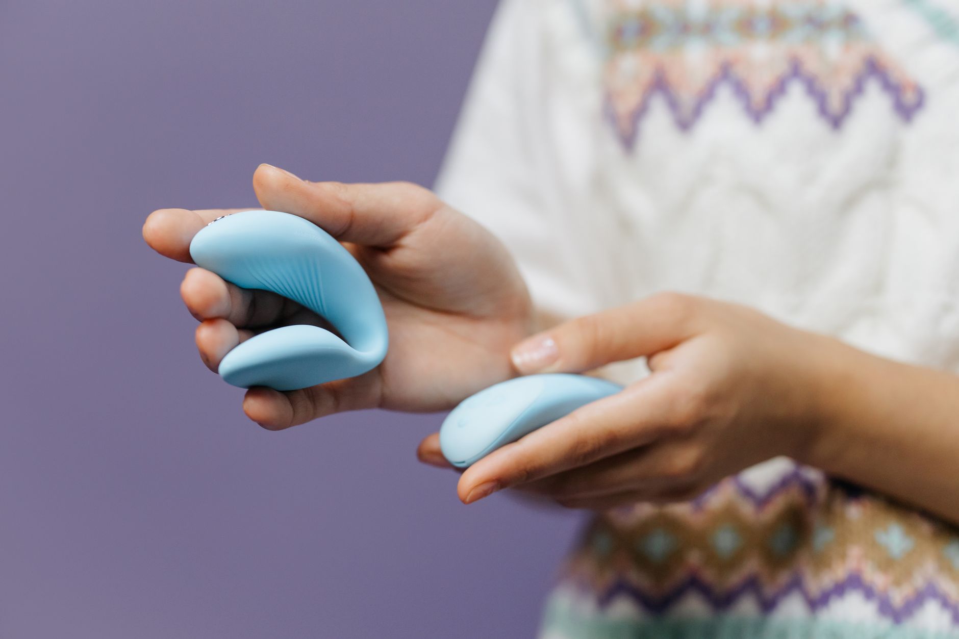 Hand hält einen blauen Zitronenvibrator vor violettem Hintergrund