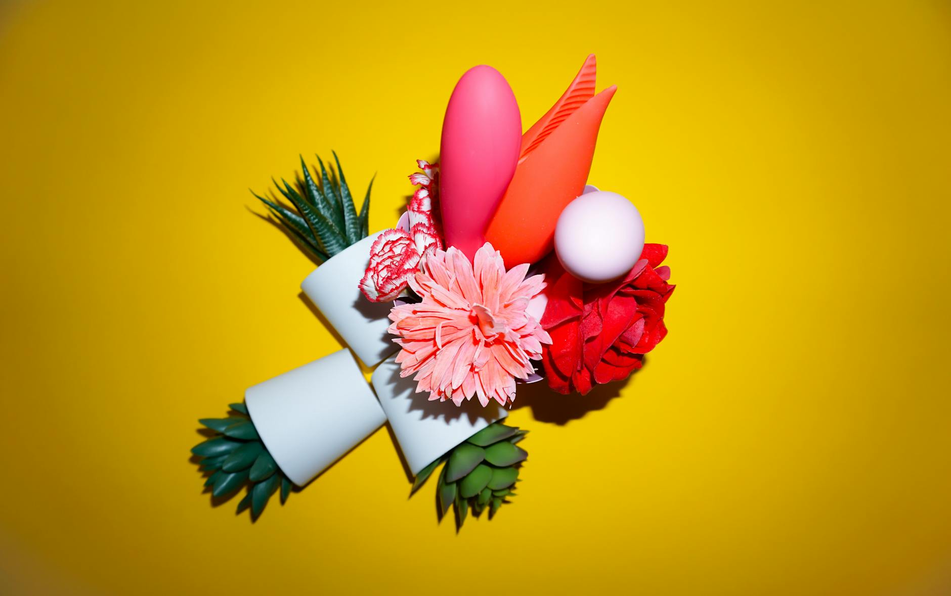 Rosa Vibrator auf lila Hintergrund mit Herzconfetti und Kerzen für romantische Stimmung