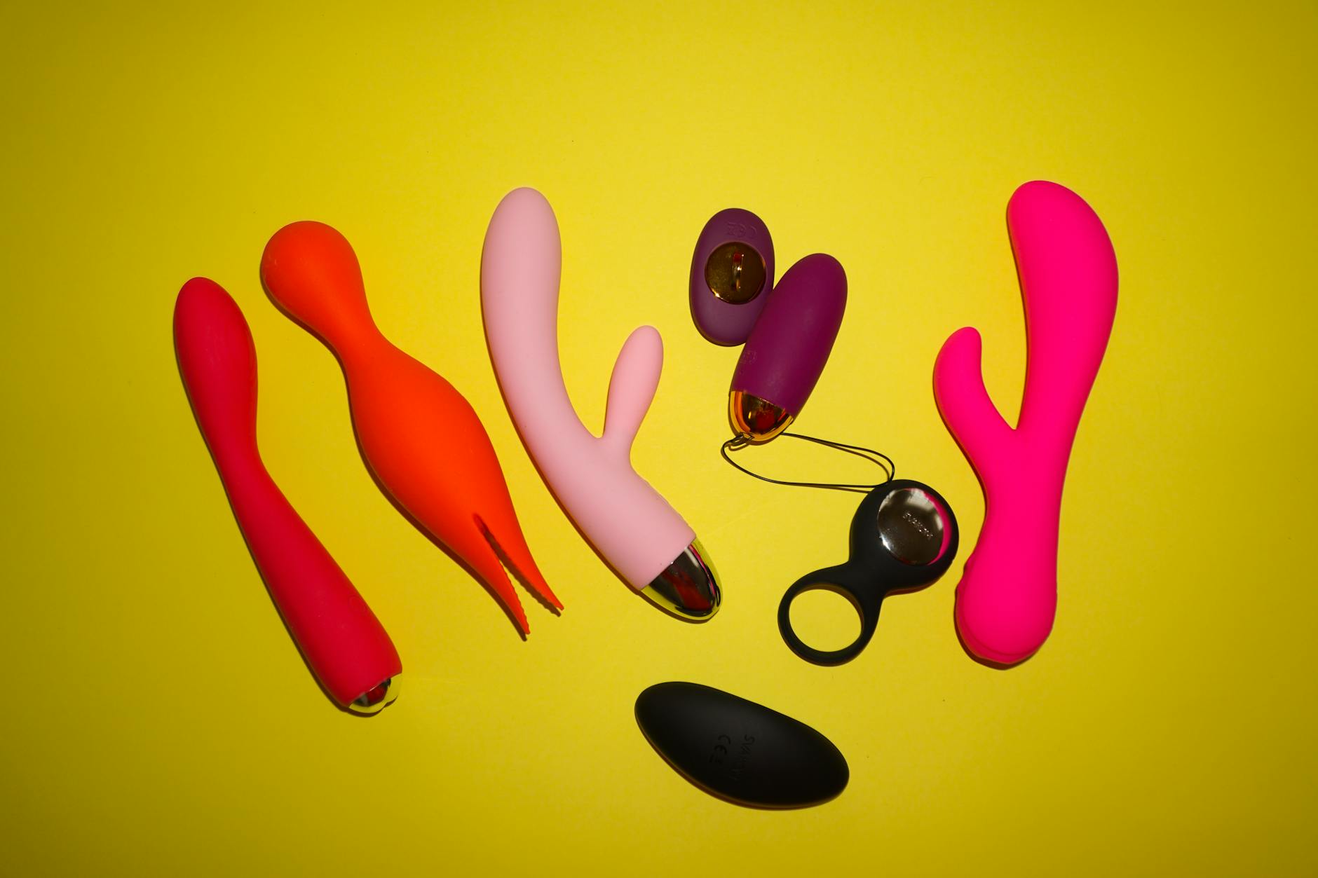 Farbenfrohe Vibratorensammlung auf leuchtendem gelbem Hintergrund mit verschiedenen Formen und Designs